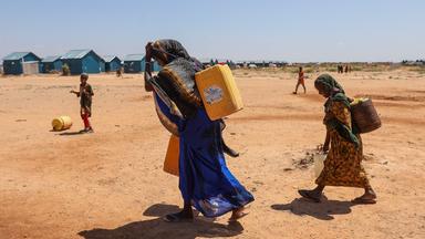 Eine Frau und ihre Kinder tragen Wasserkanister im Flüchtlingslager Ladan bei Dollow in Somalia.