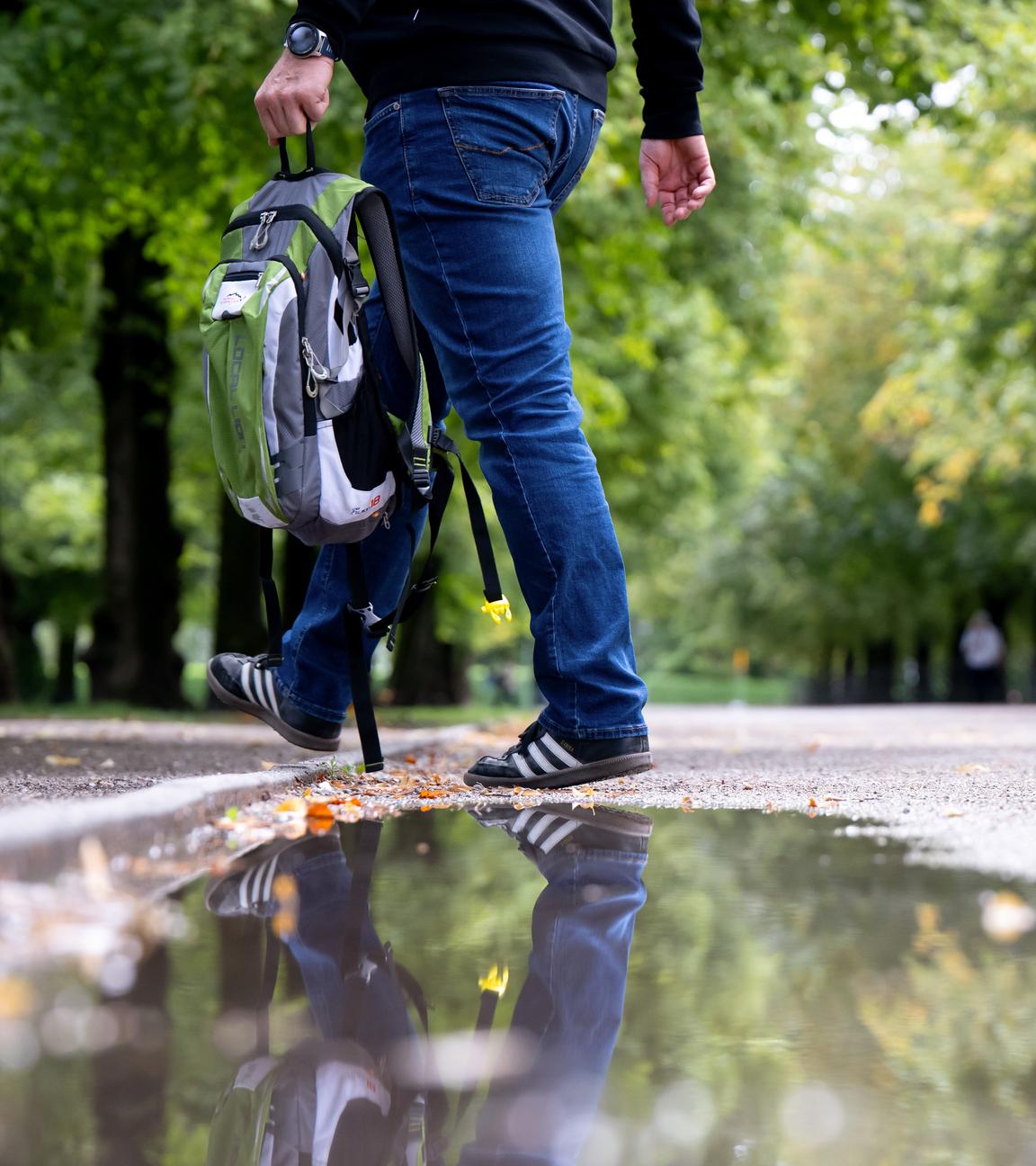 Ein Mann geht durch den Hofgarten und spiegelt sich in einer Pfütze. Der Sommer in Deutschland ist warm, lange Zeit trocken und übermäßig sonnig gewesen. Ein «relativ kühler und ausgesprochen nasser» Juli milderte die Trockenheit zwischenzeitlich, wie der Deutsche Wetterdienst (DWD) nach ersten Auswertungen seiner rund 2.000 Messstationen mitteilte