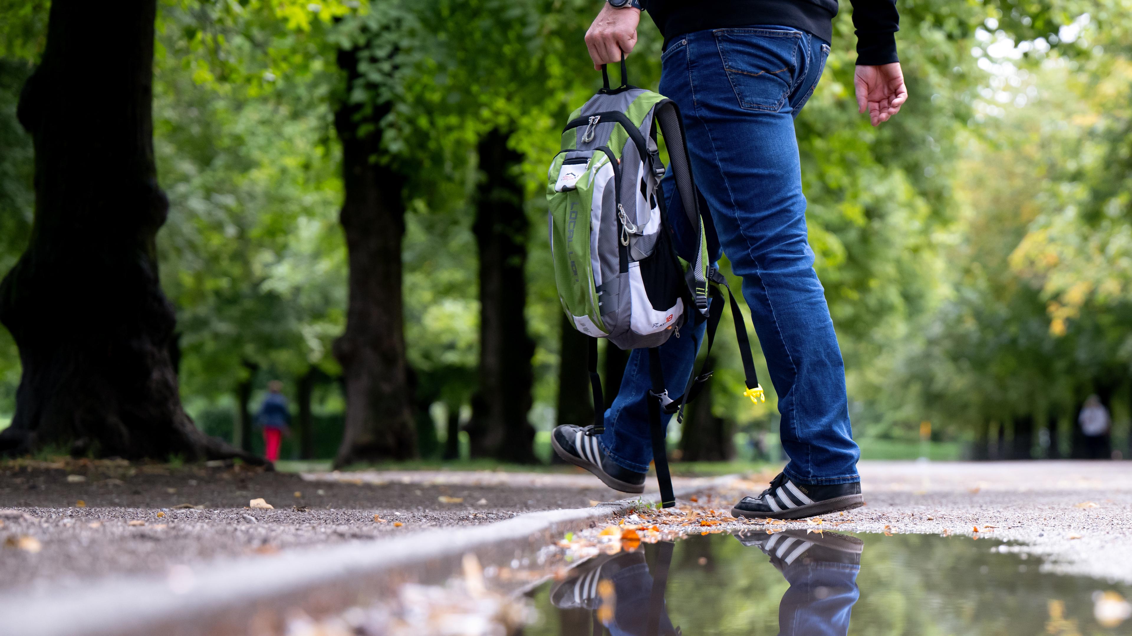 Ein Mann geht durch den Hofgarten und spiegelt sich in einer Pfütze. Der Sommer in Deutschland ist warm, lange Zeit trocken und übermäßig sonnig gewesen. Ein «relativ kühler und ausgesprochen nasser» Juli milderte die Trockenheit zwischenzeitlich, wie der Deutsche Wetterdienst (DWD) nach ersten Auswertungen seiner rund 2.000 Messstationen mitteilte