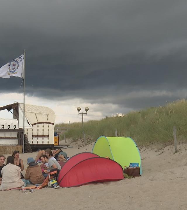 Touristen am Strand bei schlechtem Wetter