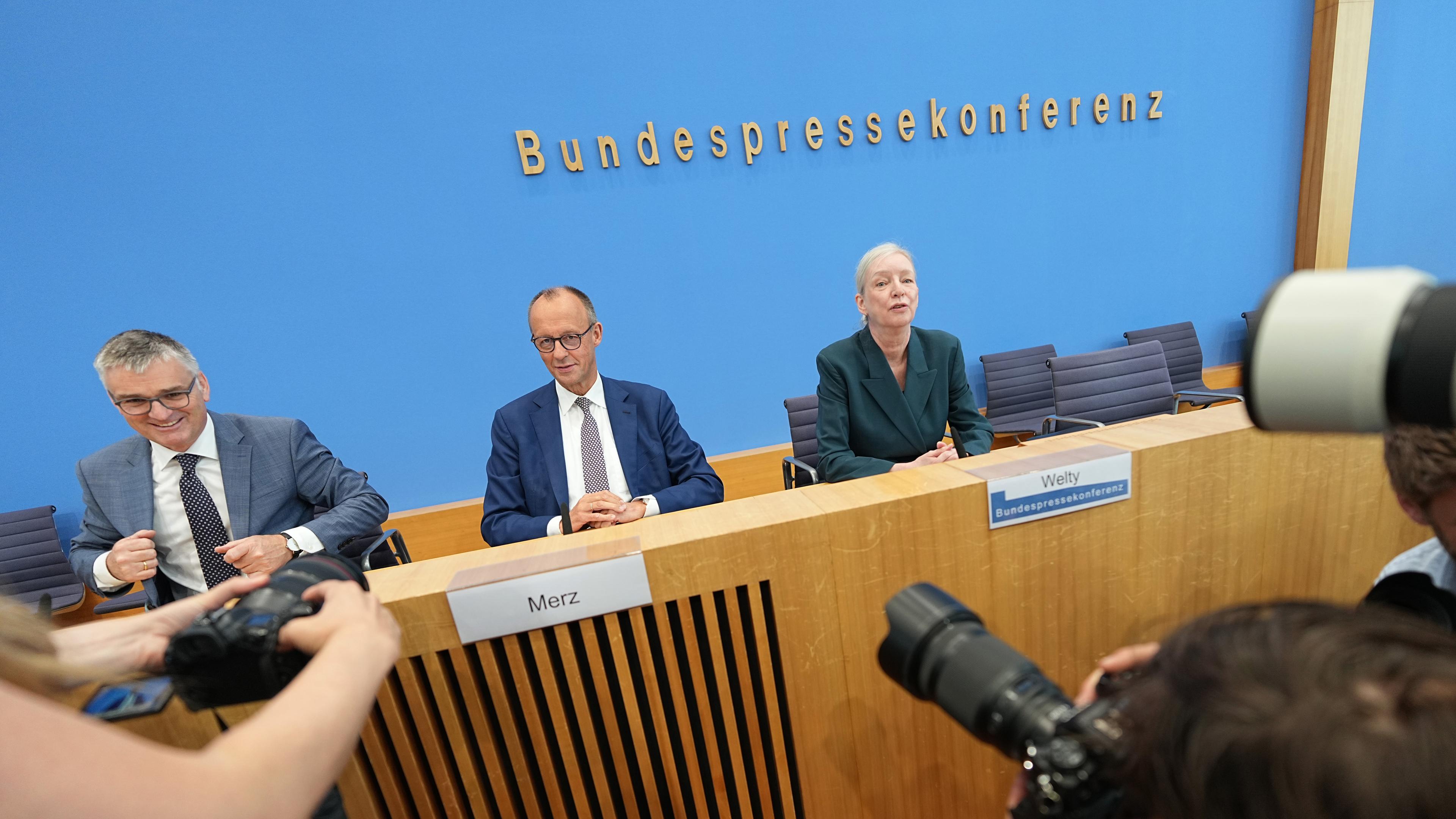 Bundeskanzler Friedrich Merz (CDU, M) sitzt mit Stefan Kornelius, Sprecher der Bundesregierung, und der Journalistin Ute Welty, die die Pressekonferenz leitet, bei seiner Sommer-Pressekonferenz in der Bundespressekonferenz. 