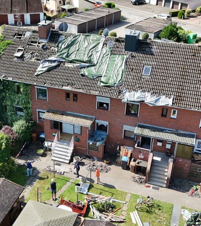 Provisorische Planen bedecken das durch ein Unwetter abgedeckte Dach eines Reihenhauses