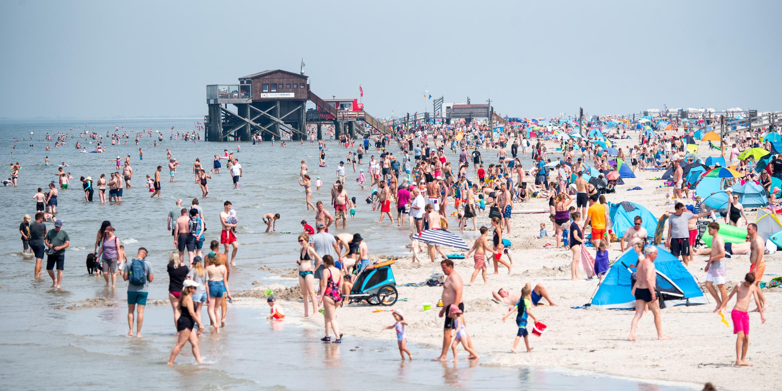 Schleswig-Holstein, Sankt Peter-Ording: Zahlreiche Touristen sind bei Sonnenschein am Strand an der Nordsee unterwegs.