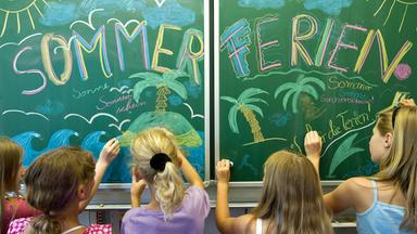 Schülerinnen einer 5. Klasse der Evangelischen Grundschule in Frankfurt (Oder) gestalten vor der Zeugnisausgabe und dem Beginn der Sommerferien eine Schultafel in ihrem Klassenraum.