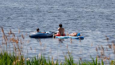 Drei Menschen liegen am 23.05.2026 auf dem Wasser der Außenalster in Hamburg.