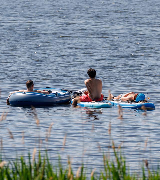 Drei Menschen liegen am 23.05.2026 auf dem Wasser der Außenalster in Hamburg.