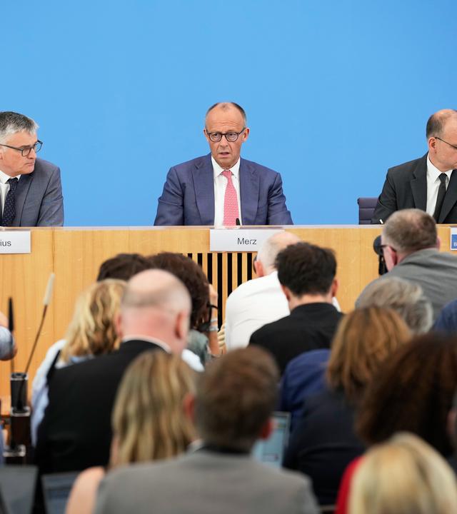 Bundeskanzler Friedrich Merz bei der Sommerpresssekonferenz. Im Vordergrund Journalisten, die Fragen stellen.