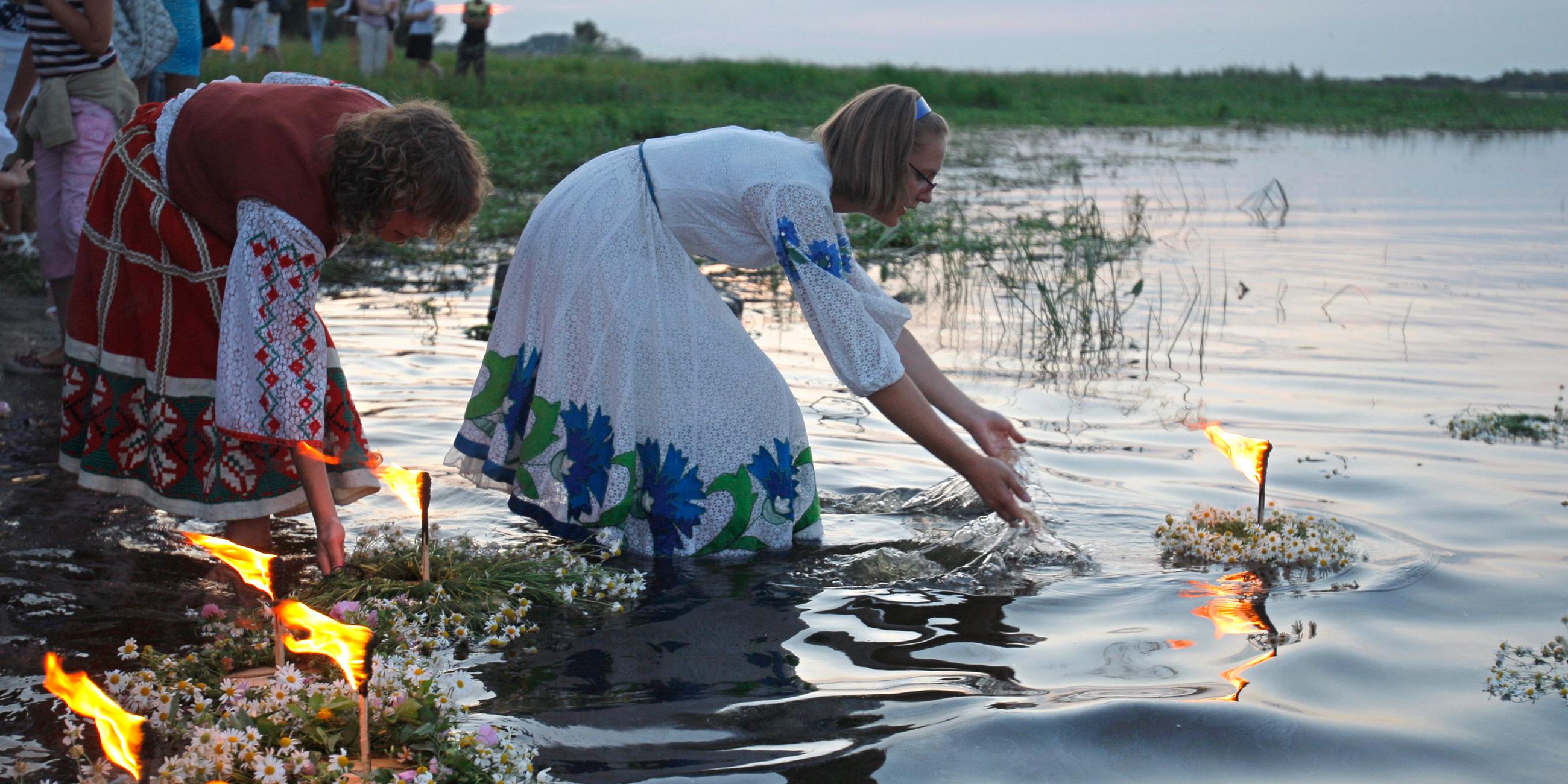 Mädchen setzen brennende Blumenkerzen in einen Fluss.