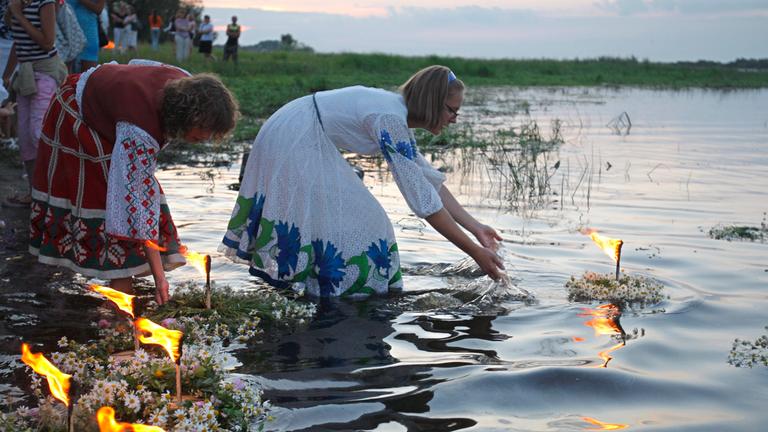 Mädchen setzen brennende Blumenkerzen in einen Fluss.