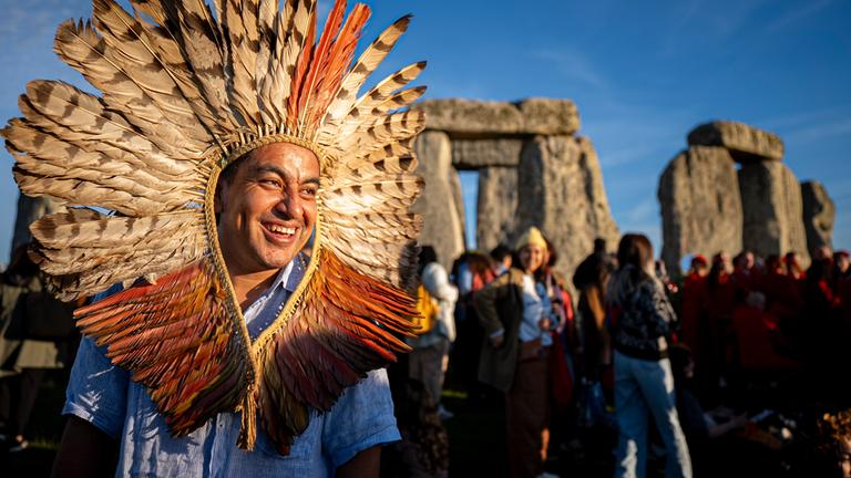 Menschen begrüßen die Sonne in Stonehenge bei Sonnenaufgang am Tag der Sommersonnenwende, dem längsten Tag des Jahres.