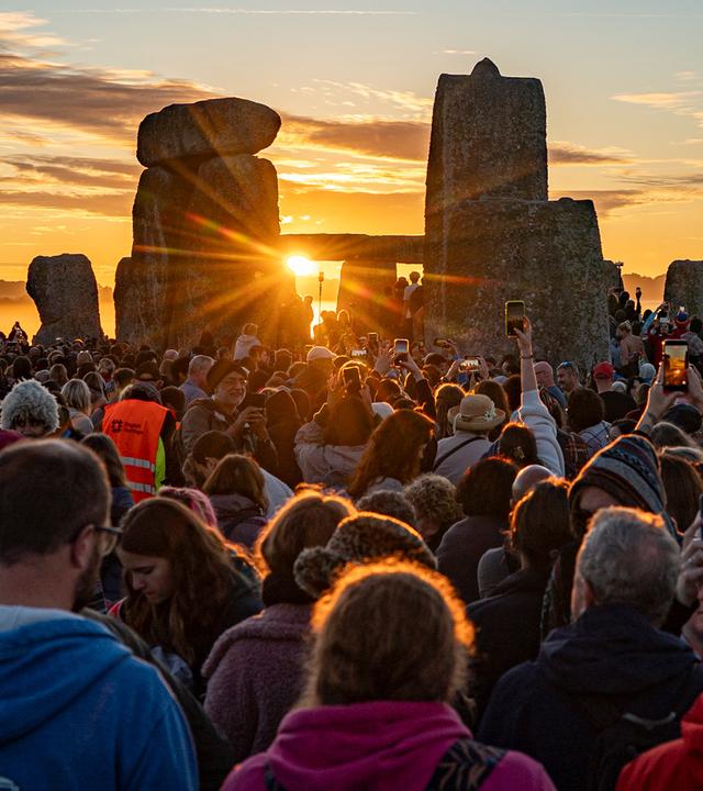 Menschen begrüßen die Sonne in Stonehenge bei Sonnenaufgang am Tag der Sommersonnenwende, dem längsten Tag des Jahres.