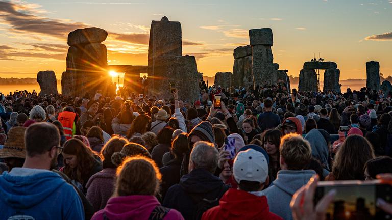 Menschen begrüßen die Sonne in Stonehenge bei Sonnenaufgang am Tag der Sommersonnenwende, dem längsten Tag des Jahres.