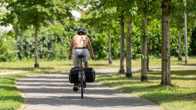  Ein Mann fährt oberkörperfrei in Freiburg im Breisgau mit seinem Fahrrad auf einem Fahrradweg.
