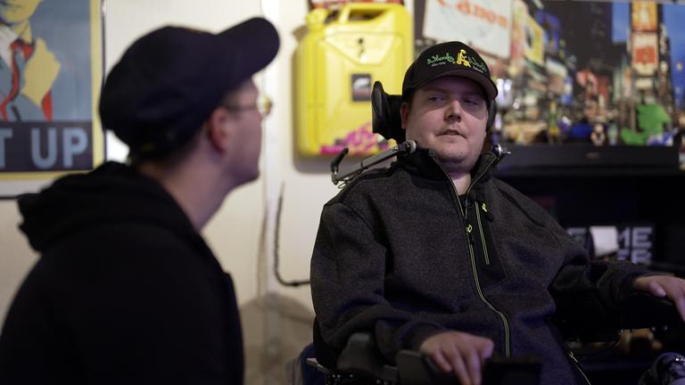 Zwei Männer sitzen in einem Gaming-Zimmer und unterhalten sich.