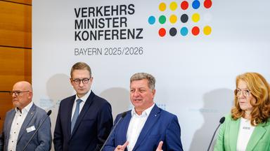 Pressekonfernz der Verkehrsminister. Vier Minister stehen an einem Rednerpult. Im Hintergund ist eine weiße Wand mit der Aufschrift Verkehrsministerkonferenz und bunten Punkten
