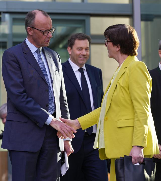 Friedrich Merz und Saskia Esken geben sich die Hand vor dem Marie-Elisabeth-Lüders-Haus. Im Hintergrund sind Lars Klingbeil und Markus Söder zu sehen.