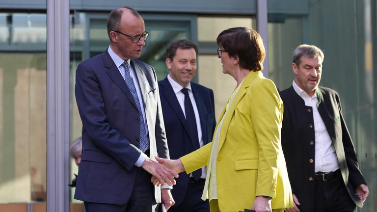 Friedrich Merz und Saskia Esken geben sich die Hand vor dem Marie-Elisabeth-Lüders-Haus. Im Hintergrund sind Lars Klingbeil und Markus Söder zu sehen.