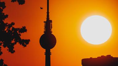 Die untergehende Sonne zeichnet sich ab hinter dem Fernsehturm in Berlin, 19.06.2026.
