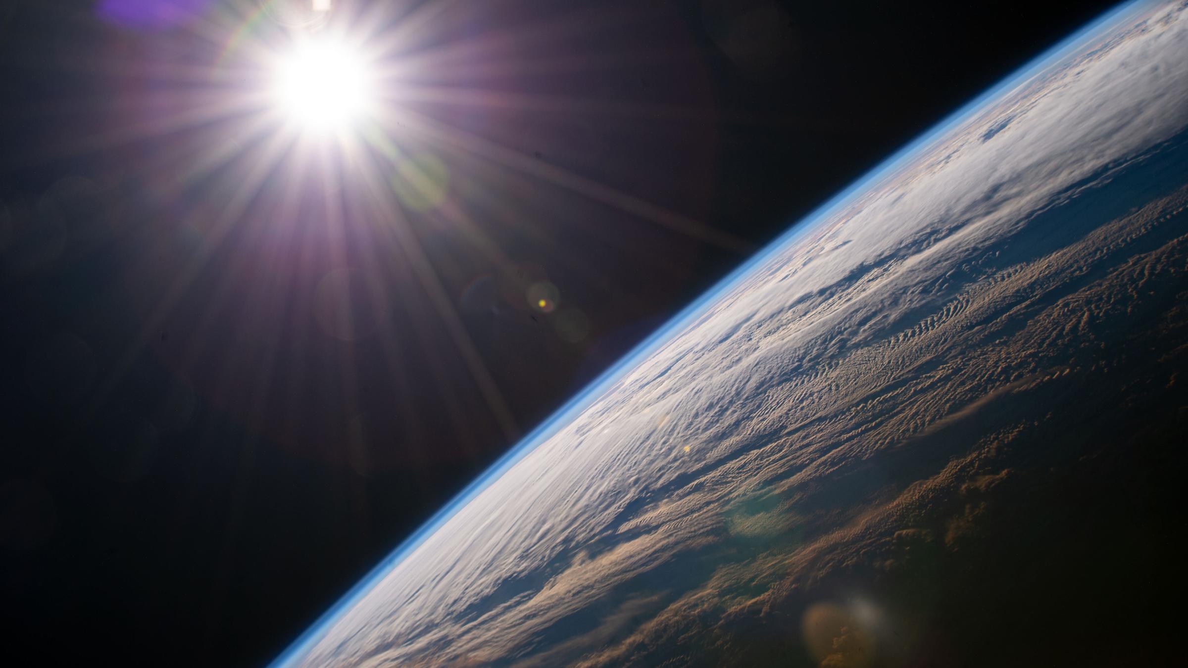 30.12.2021, ---, ISS: Die Sonne scheint über dem Horizont der Erde, während die Internationale Raumstation über der kanadischen Provinz Quebec kreist. 