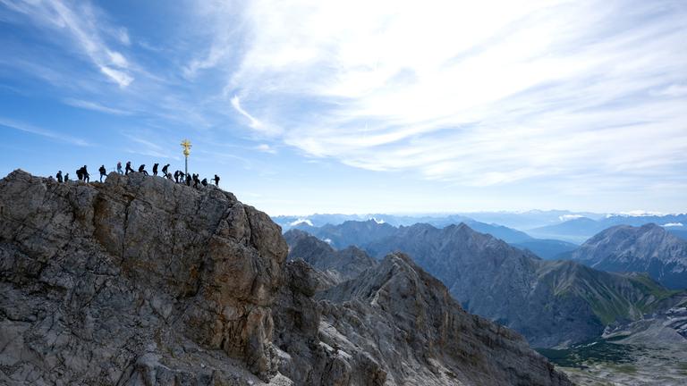 Bayern, Grainau: Ausflügler genießen das schöne Wetter am Gipfelkreuz auf der Zugspitze.