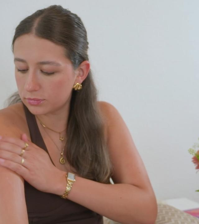 Eine junge Frau schaut sich ihren Arm an.