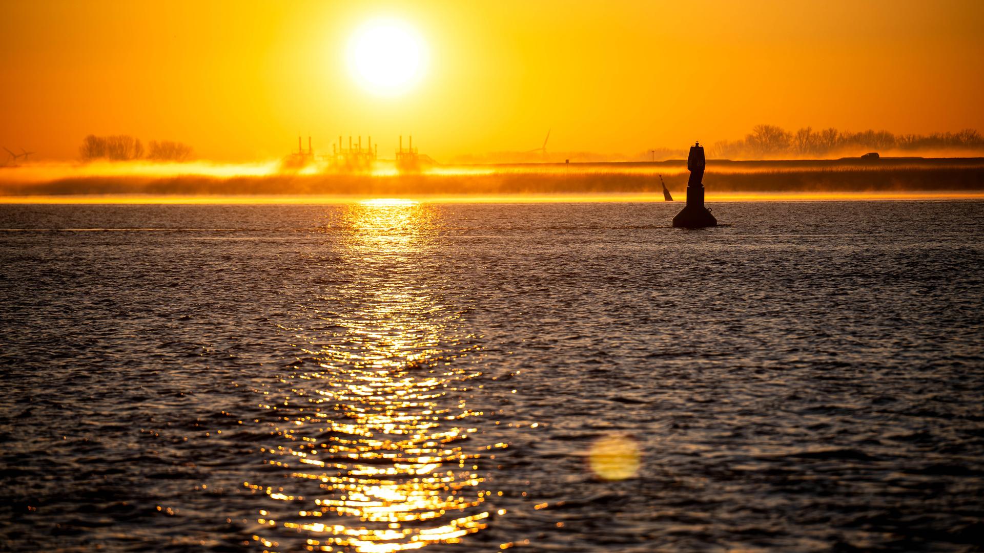 Die Sonne geht über der Wesermündung auf.