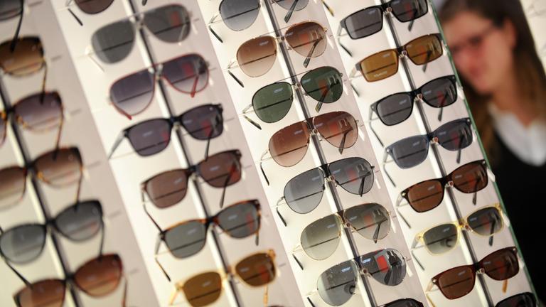 Viele Sonnenbrillen sind an einer Wand ausgestellt.
