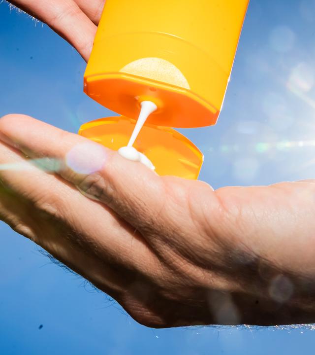 Ein Mann gibt Sonnenmilch aus einer Tube in seine Hand.