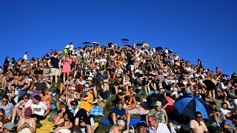 Menschen betrachten eine partielle Sonnenfinsternis am Olympiaberg im Münchner Olympiapark.