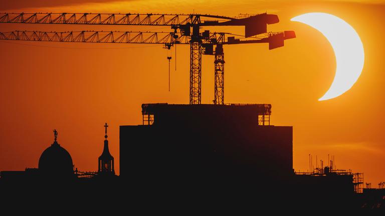 Partielle Sonnenfinsternis in Berlin vor Kränen im Abendrot.