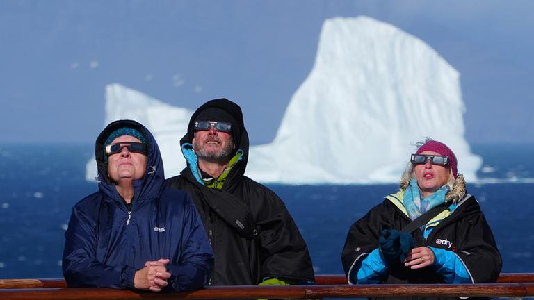 Passagiere an Bord eines Kreuzfahrtschiffs beobachteten den Beginn der totalen Sonnenfinsternis vor der Küste Grönlands.