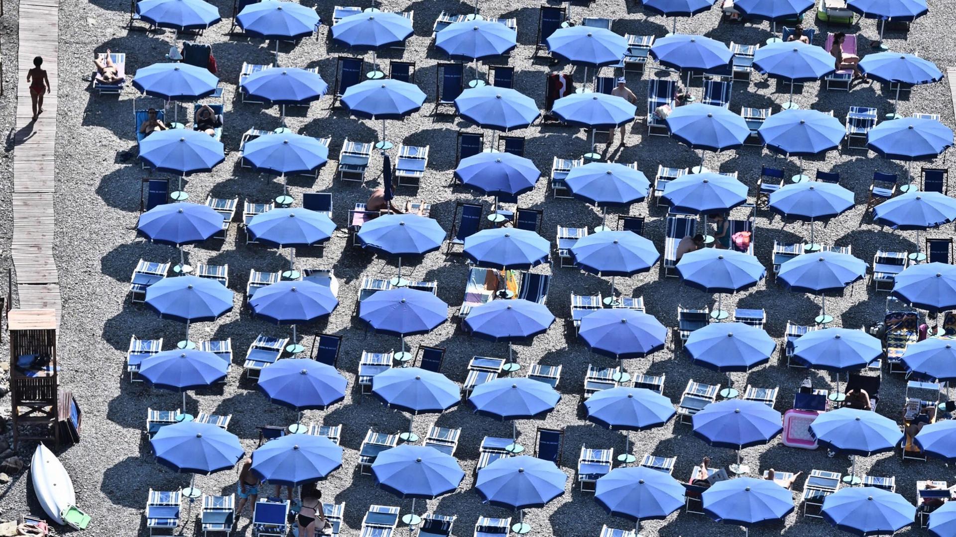 Blaue Sonnenschirme sind an italienischem Strand dicht beieinander aufgestellt