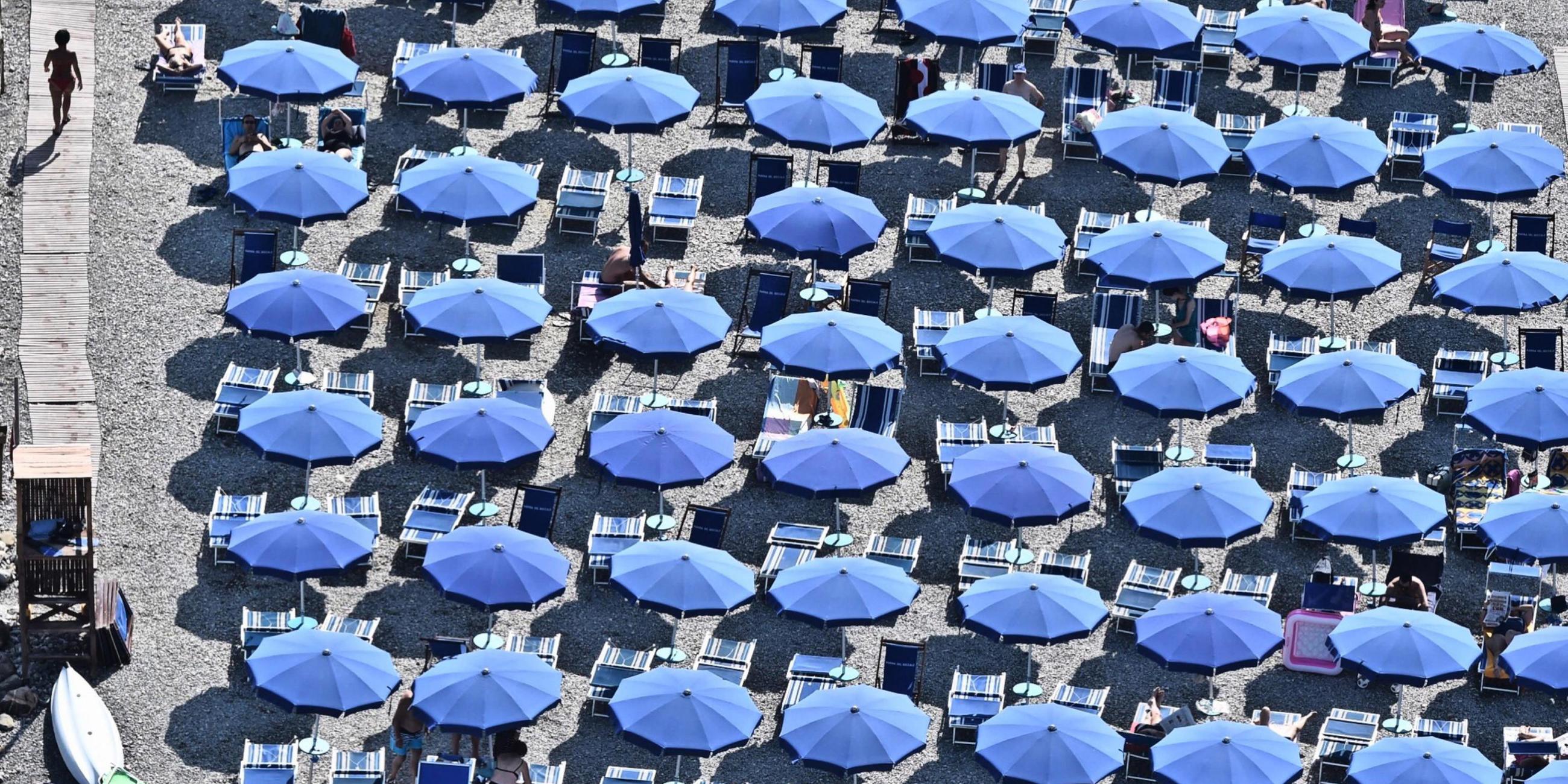 Blaue Sonnenschirme sind an italienischem Strand dicht beieinander aufgestellt