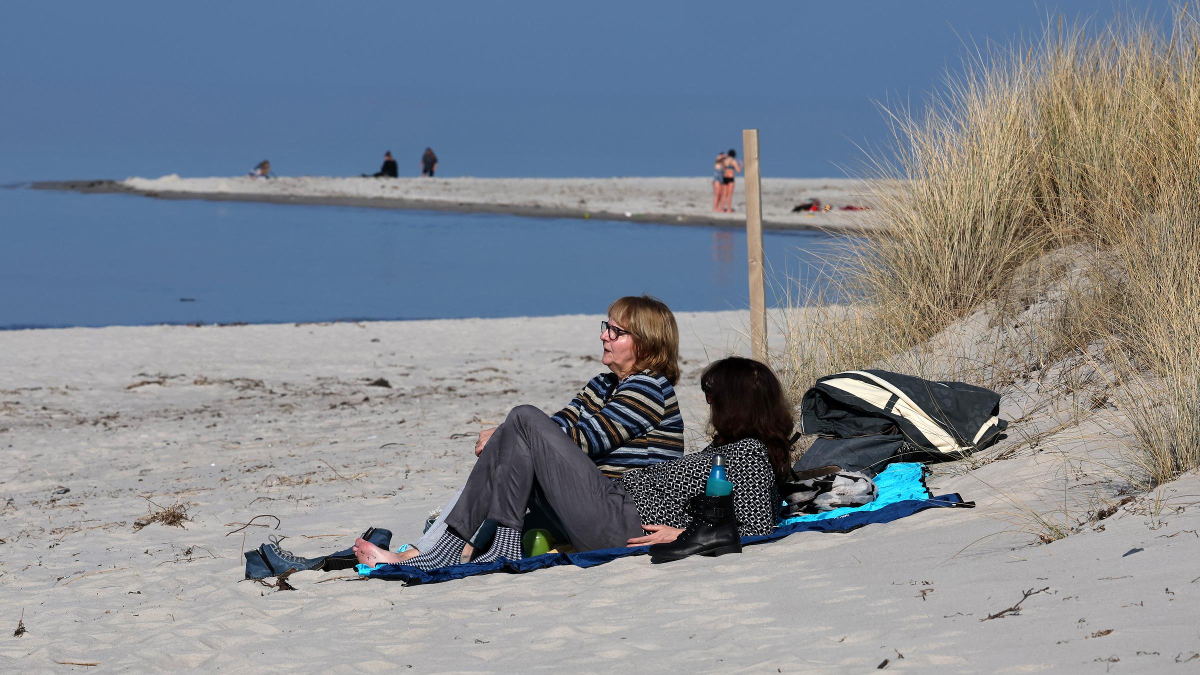 Mecklenburg-Vorpommern, Wustrow: Menschen sitzen am Ostseestrand bei milden Temperaturen.