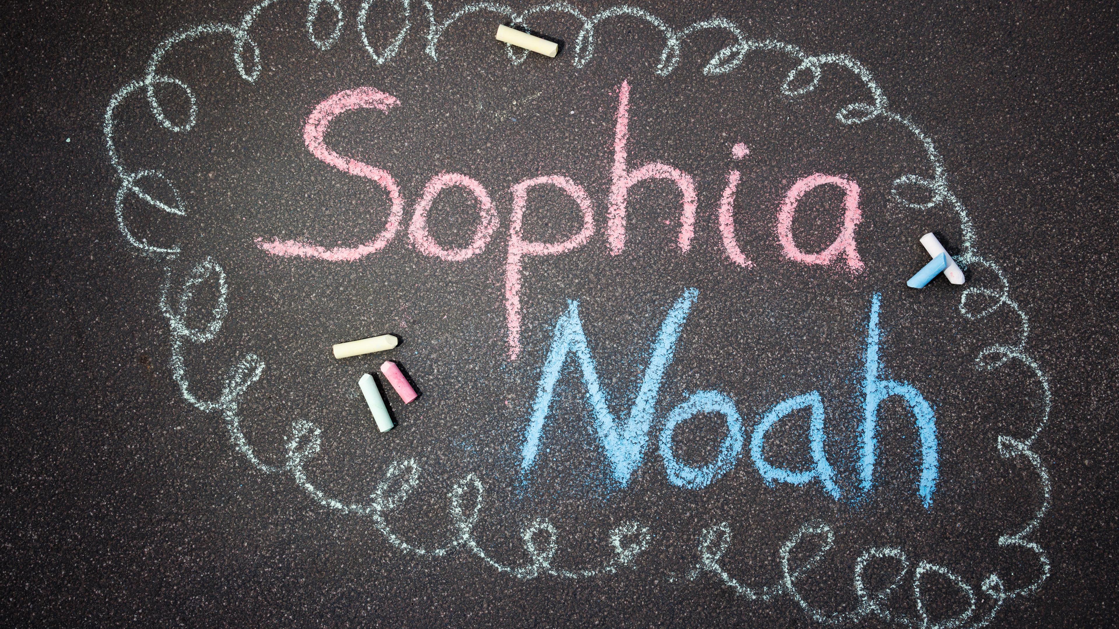 ILLUSTRATION - Mit Straßenkreide sind die Namen Sophia und Noah auf den Boden geschrieben. 