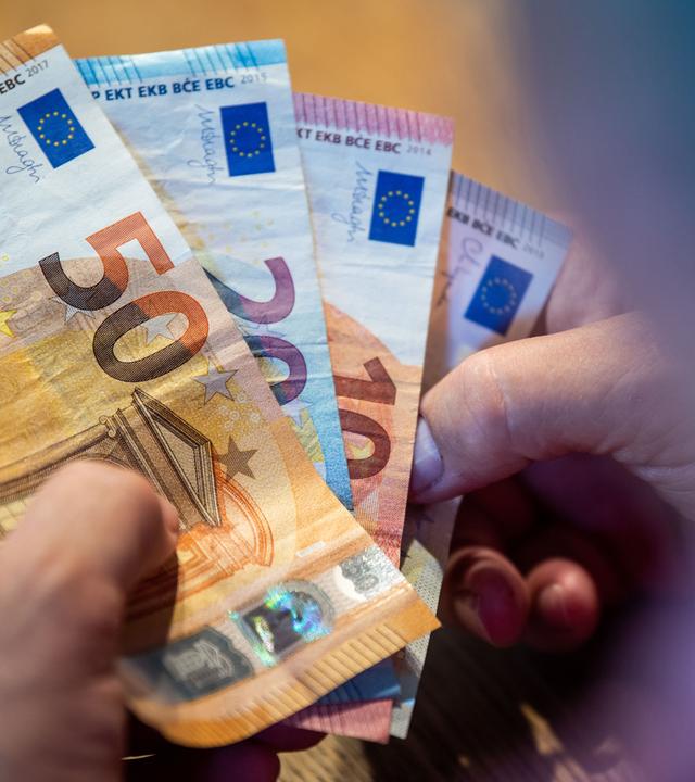 Symbolbild: Ein älterer Mann zählt Geld an einem Tisch.