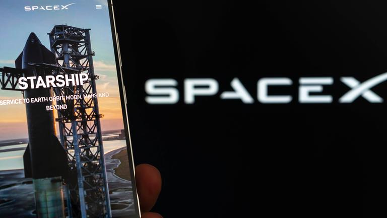 Symbolbild: SpaceX-Logo und Starship auf dem Smartphone-Bildschirm.