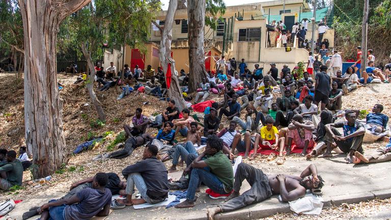 Migranten ruhen sich vor dem Übergangszentrum für Einwanderer (CETI) aus, nachdem sie von Marokko aus in die spanische Exklave Ceuta gelangt sind.