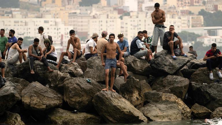 Spanien, Ceuta: Migranten sitzen auf Felsen, nachdem sie durch die Gewässer nahe der Grenze zu Marokko geschwommen sind