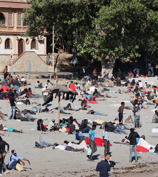 Junge Migranten, die einige Tage zuvor in Ceuta angekommen sind, stehen am Trampolin Beach in Ceuta, Spanien