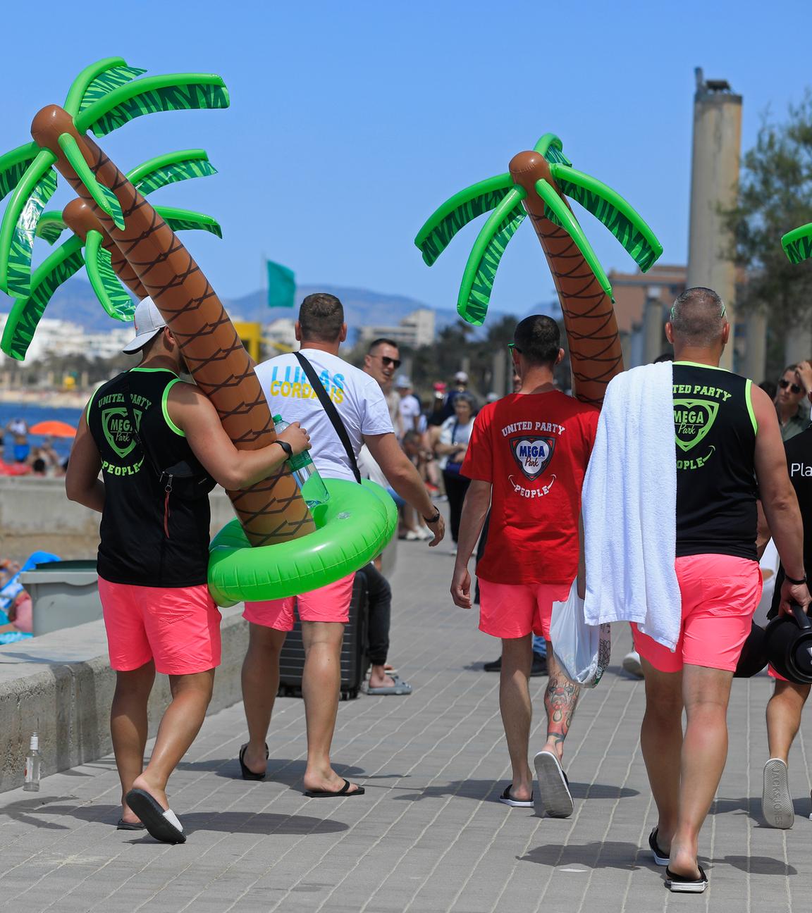 Spanien, Palma: Männer tragen an einem sonnigen Tag Plastikpalmen am Strand Arenal. Archivbild