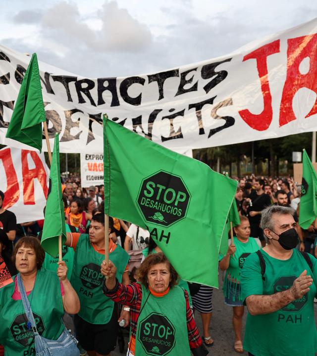 Mehrere Demonstranten halten grüne Fahnen und ein großes Banner hoch.