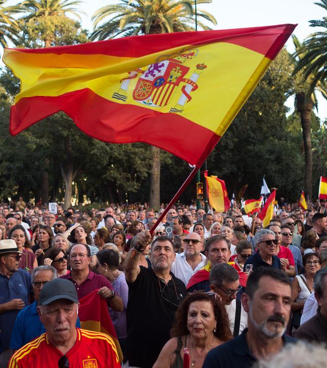 Menschen demonstrieren in Spanien mit Flaggen.