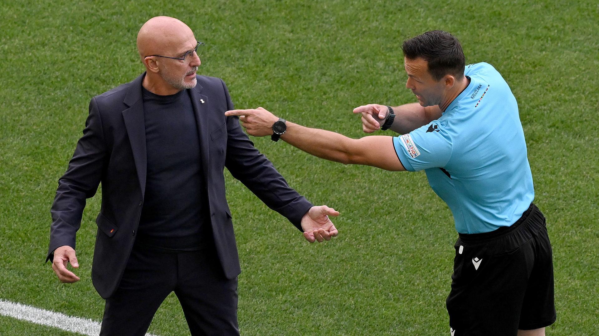 Spaniens Trainer Luis de la Fuente (l) spricht mit dem Vierten Offiziellen Ivan Kruzliak, aufgenommen am 05.07.2024