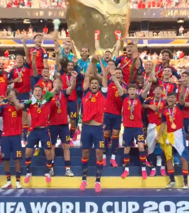 Die spanische Nationalmannschaft feiert ihren WM Sieg, währendessen steht Trump weiterhin auf der Bühne