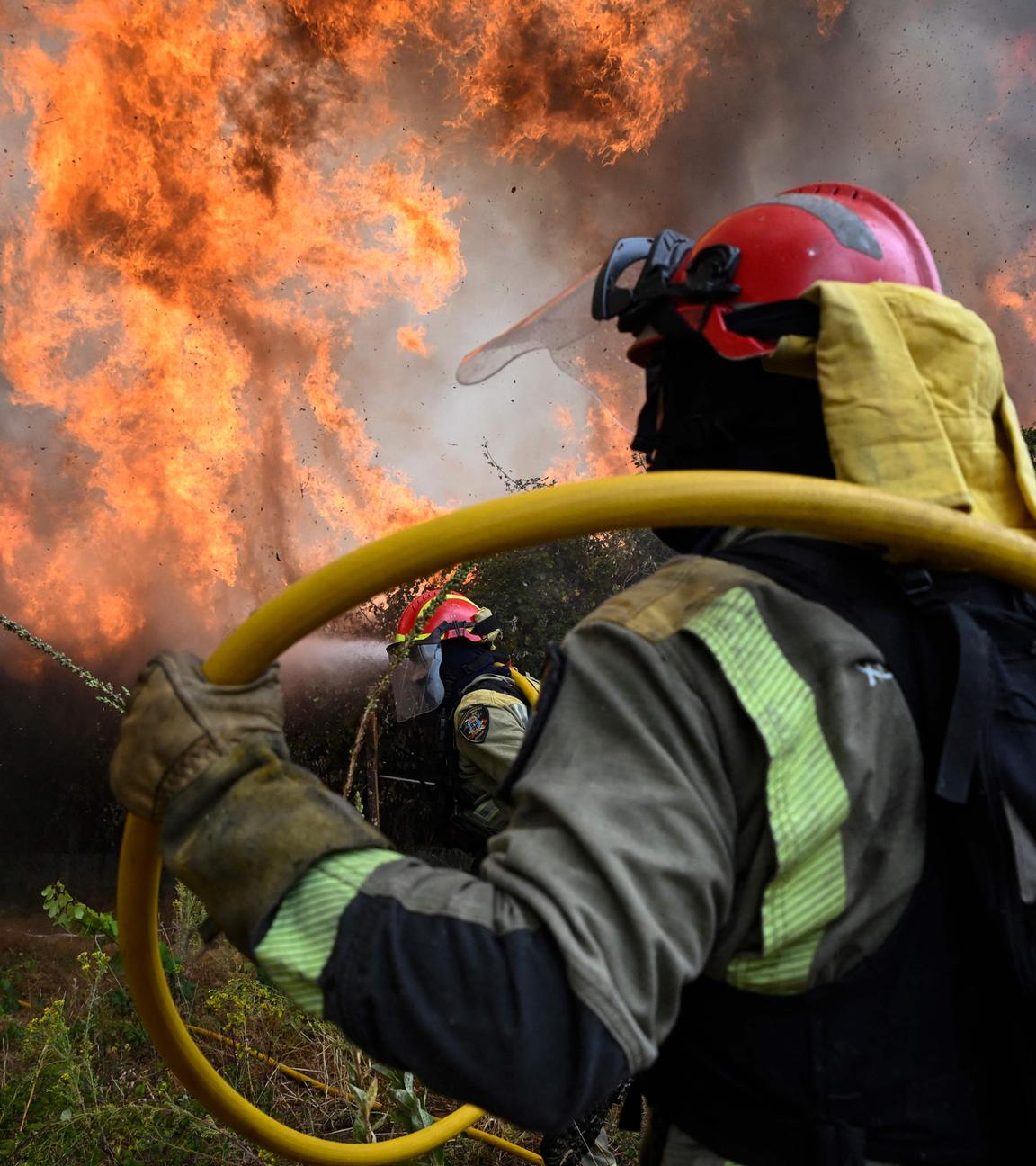 Firefighters work together to extinguish a wildfire in San Cibrao das Viñas, outside Ourense, northwestern Spain, on August 12, 2025. 