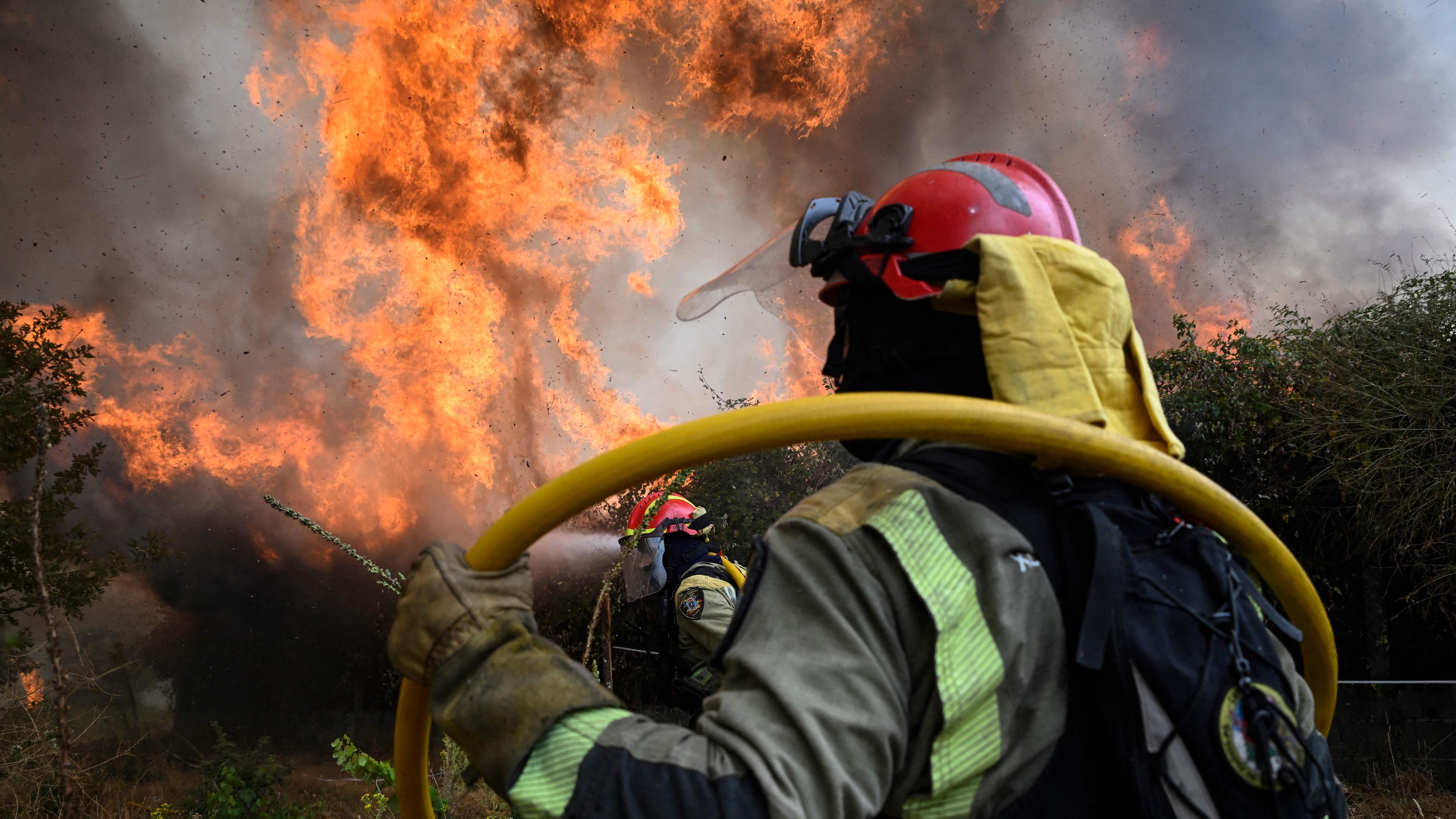 Firefighters work together to extinguish a wildfire in San Cibrao das Viñas, outside Ourense, northwestern Spain, on August 12, 2025. 
