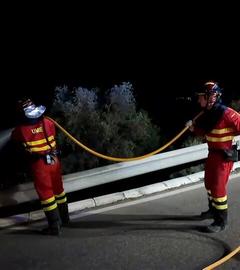 Zwei Feuerwehrkräfte sind zu sehen, wie sie an der Löschung des Waldbrandes im südspanischen Almeria beteiligt sind.