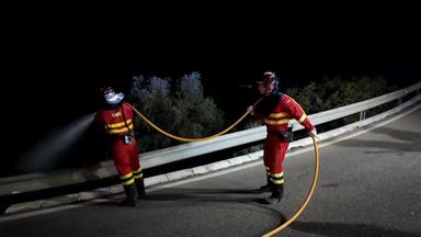 Zwei Feuerwehrkräfte sind zu sehen, wie sie an der Löschung des Waldbrandes im südspanischen Almeria beteiligt sind.