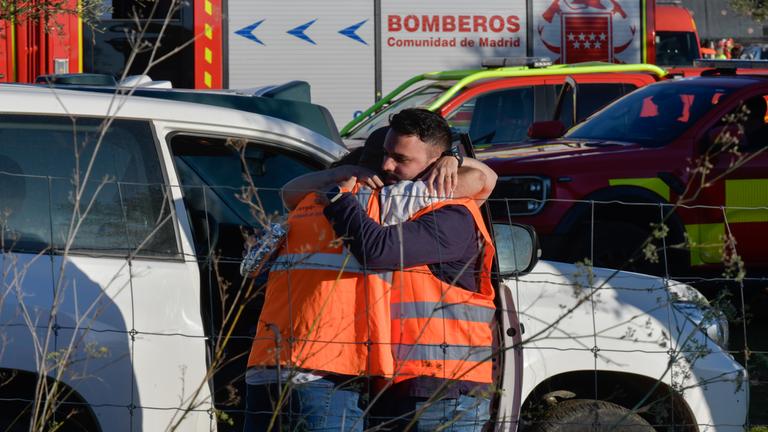 28.10.2026, Spanien, Urda: Menschen umarmen sich am Unglücksort nach dem Zusammenstoß zweier Züge. Das Unglück ereignete sich kurz vor neun Uhr, als ein Zug des privaten Bahnunternehmens Iryo zum Stehen kam und ein nachfolgender Zug der staatlichen Gesellschaft Renfe von hinten auf ihn auffuhr.
